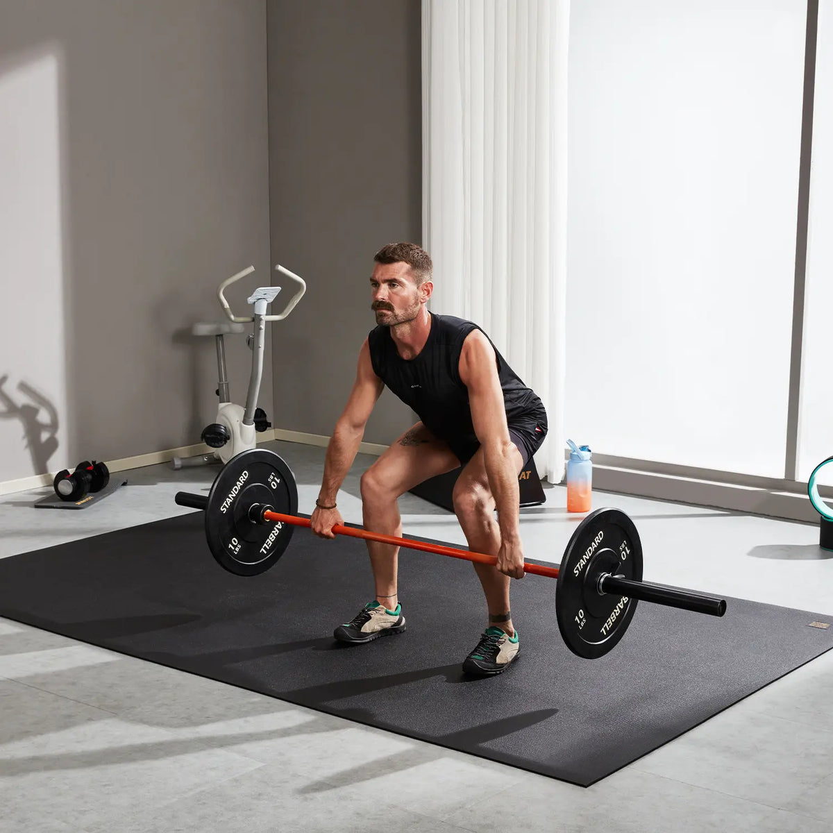 Man deadlifting a loaded barbell on a GXMMAT large exercise mat