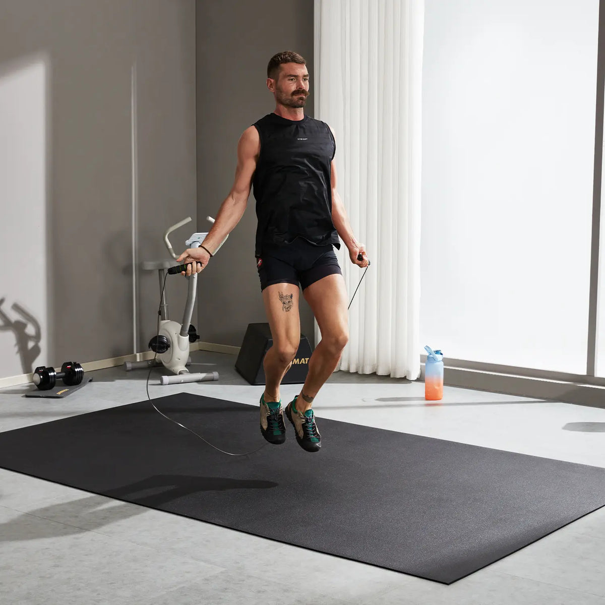 Man jumping rope on a GXMMAT large exercise mat in a bright home gym