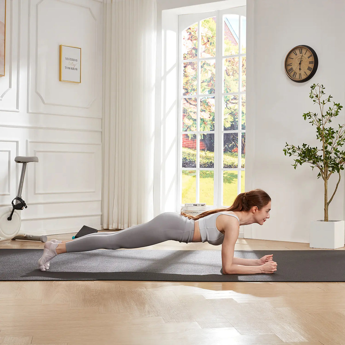 Woman holding a forearm plank on a GXMMAT large yoga mat in a bright living room
